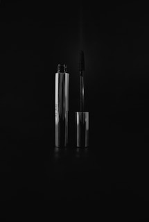 Elegant mascara wands with glossy black tubes displayed on a marble surface.