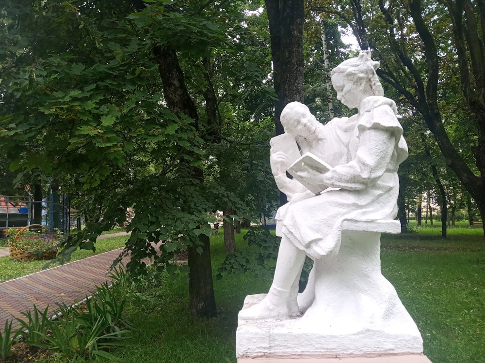 Una estatua de un hombre leyendo un libro en un parque