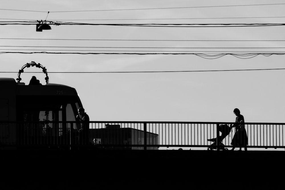 a person walking across a bridge next to a train