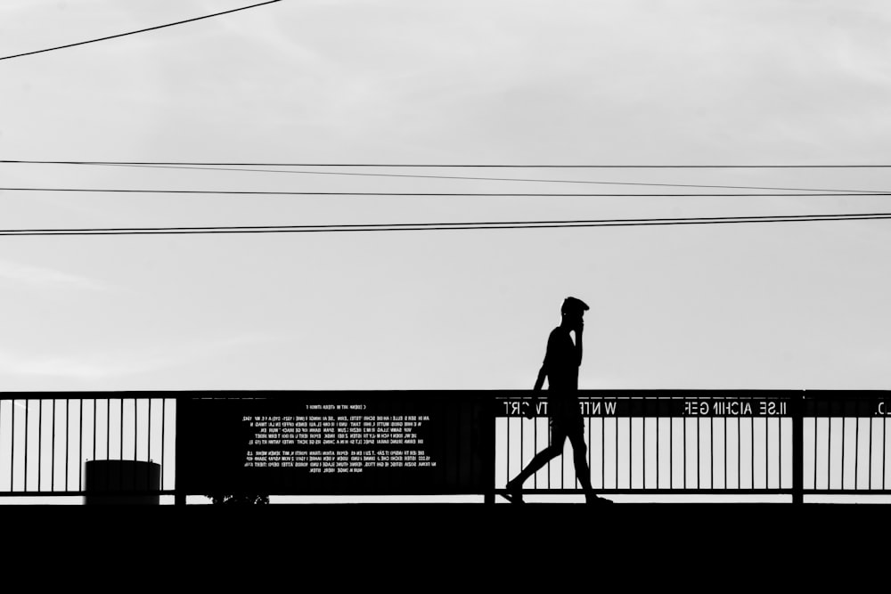 a man walking across a bridge next to power lines