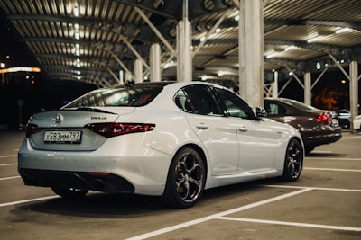 A car parked in a well-lit, secure parking spot at night with visible security cameras.