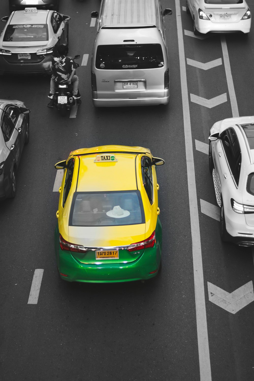 a yellow and green taxi cab driving down a street