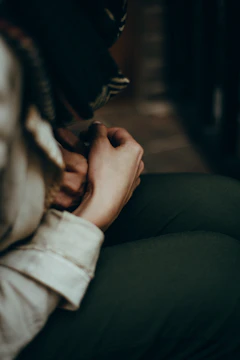 Close-up of a woman’s hands folded gently over her heart, bathed in warm champagne light.