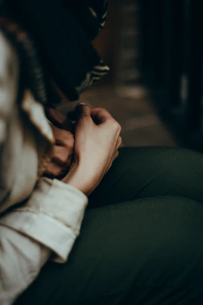 Close-up of a child's small hands resting peacefully on their knees in a calm, sunlit room.