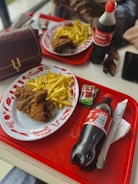 A combo meal featuring fried chicken, fries, and a soft drink on a tray