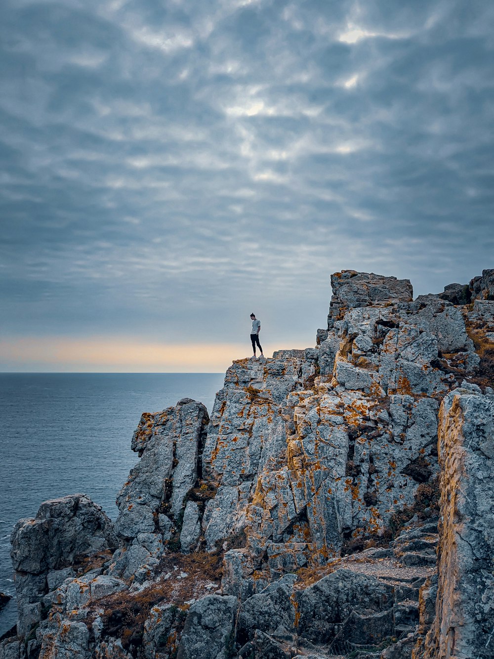 Un homme debout au sommet d’une falaise rocheuse au bord de l’océan