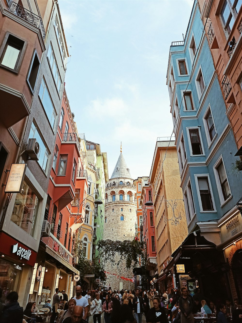 a crowd of people walking down a street next to tall buildings