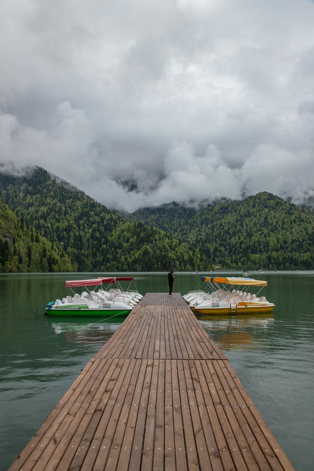 a person standing on a dock next to two boats