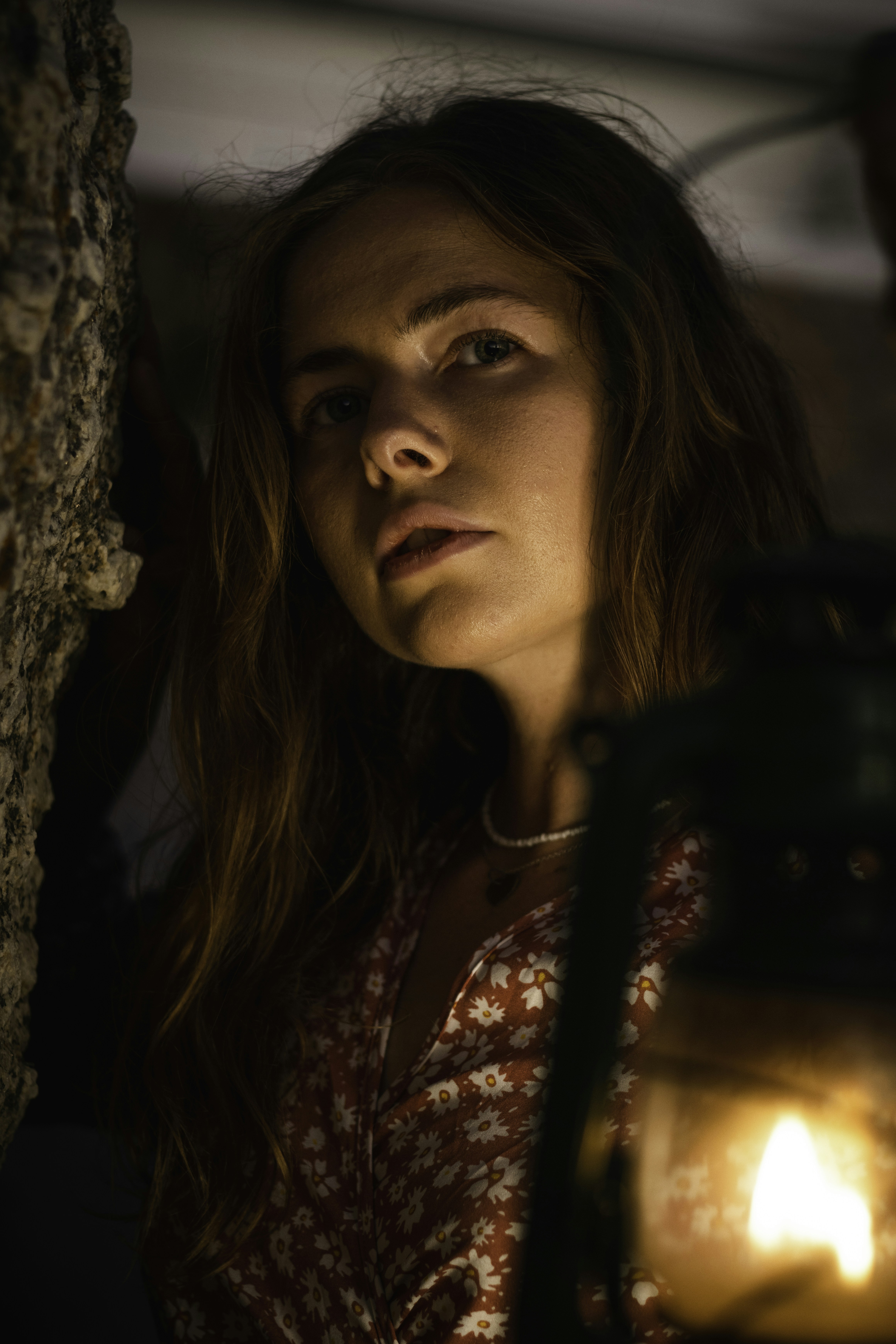 eine frau, die neben einer wand steht und eine laterne hält