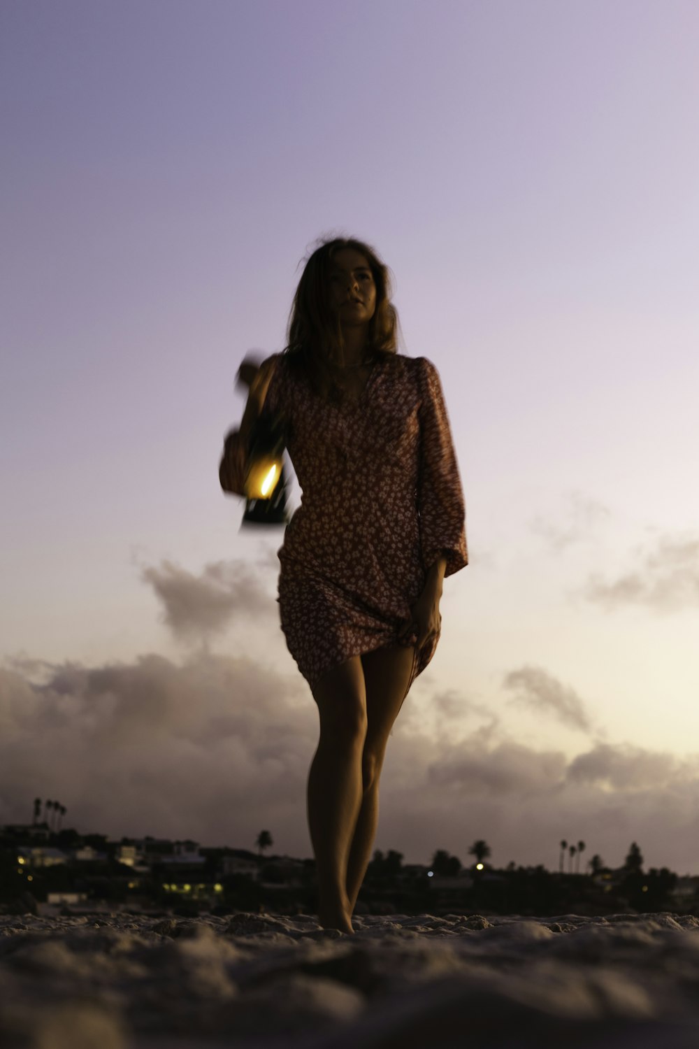 a woman in a dress is walking on the beach