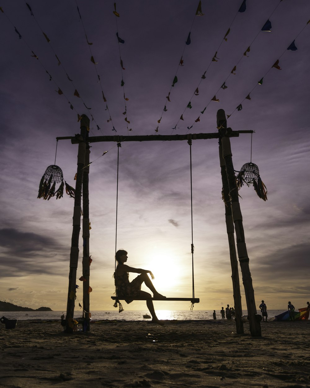 a man sitting on a swing at the beach