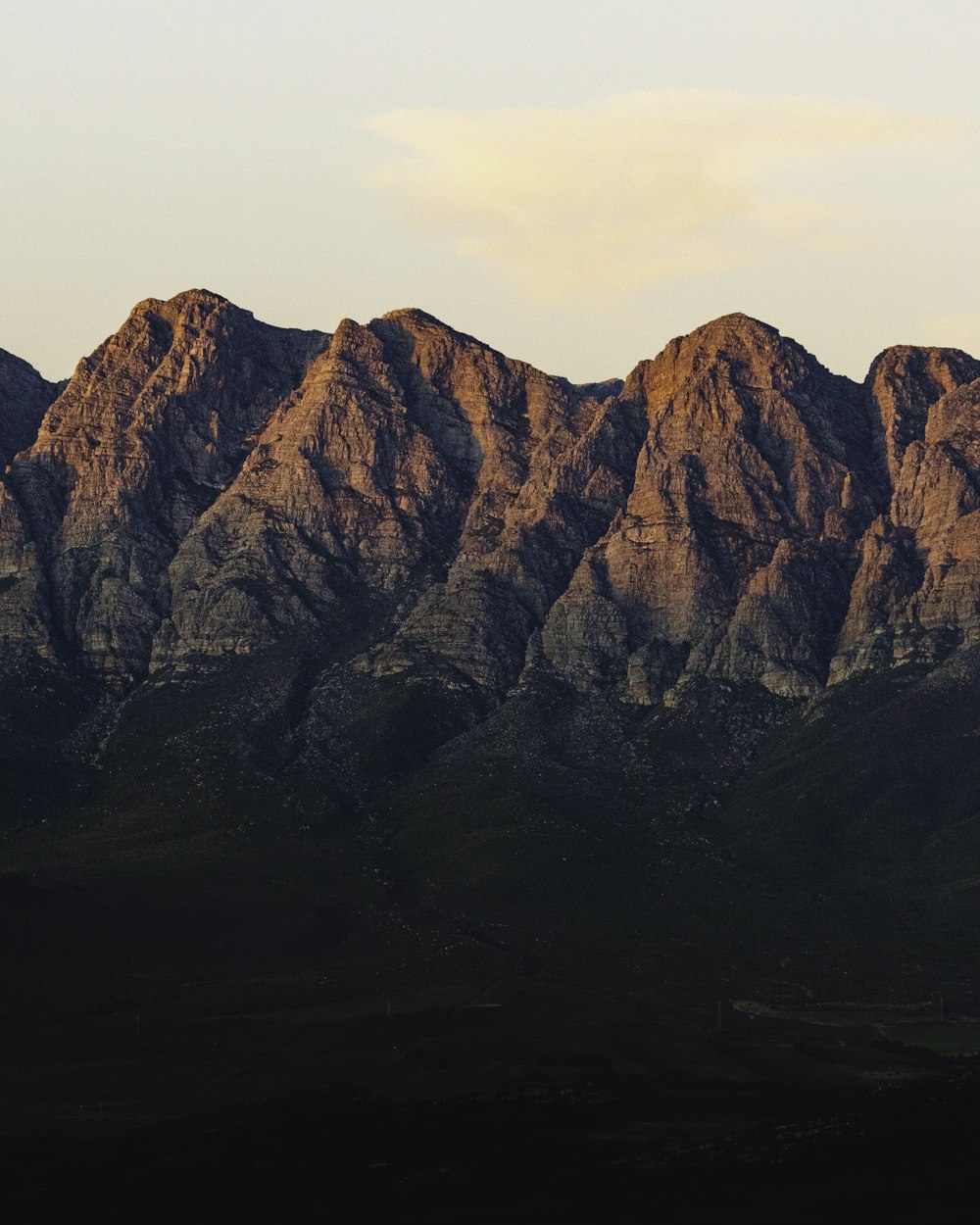 a mountain range with a few clouds in the sky