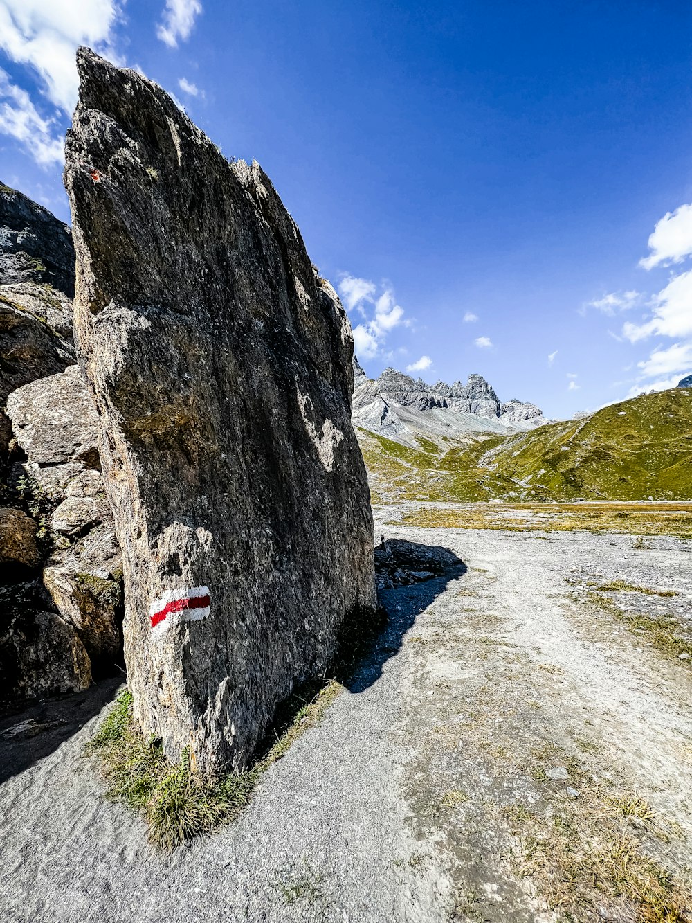 uma grande rocha sentada à beira de uma estrada de terra