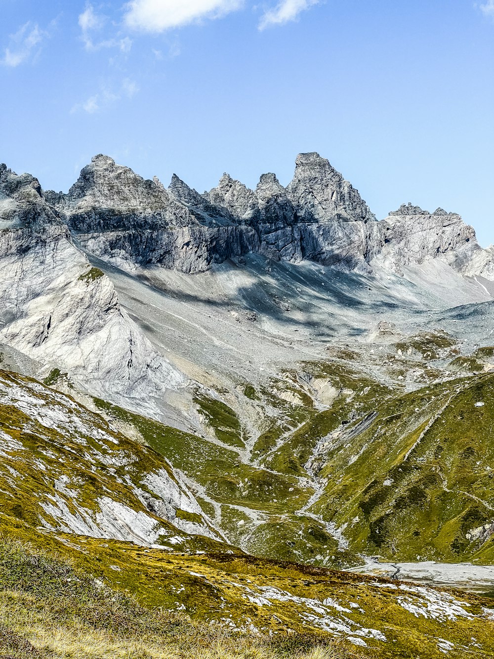 As montanhas estão cobertas de neve e grama verde