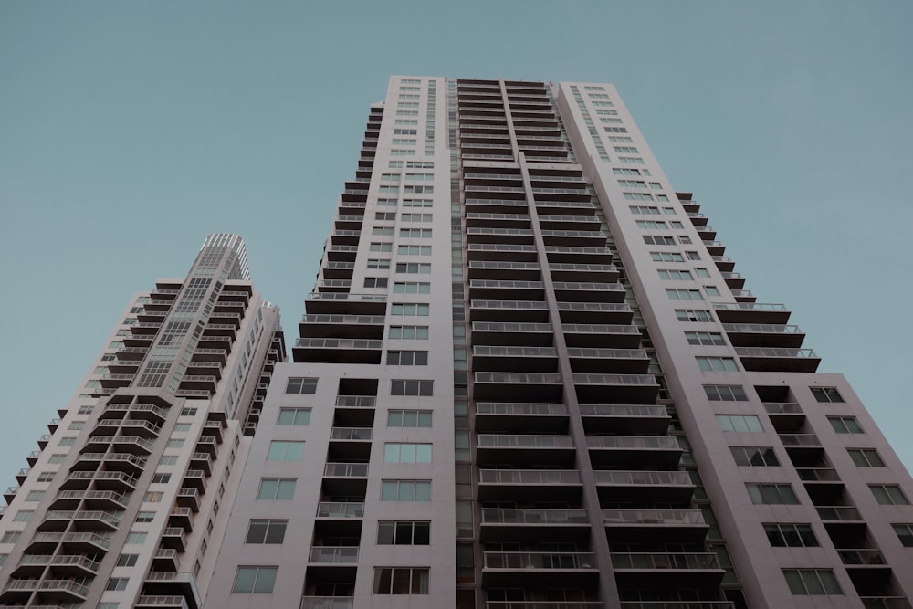 two tall buildings with balconies against a blue sky