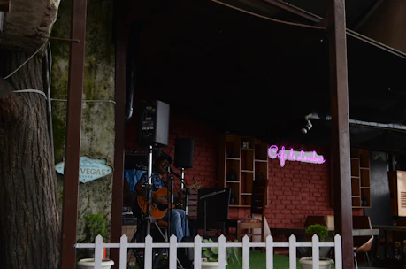 A musician playing a guitar surrounded by colorful flower arrangements in a cozy outdoor setting.