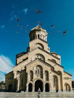 a large church with birds flying around it