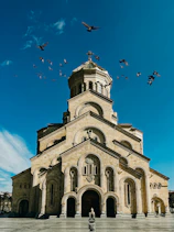 a large church with birds flying around it