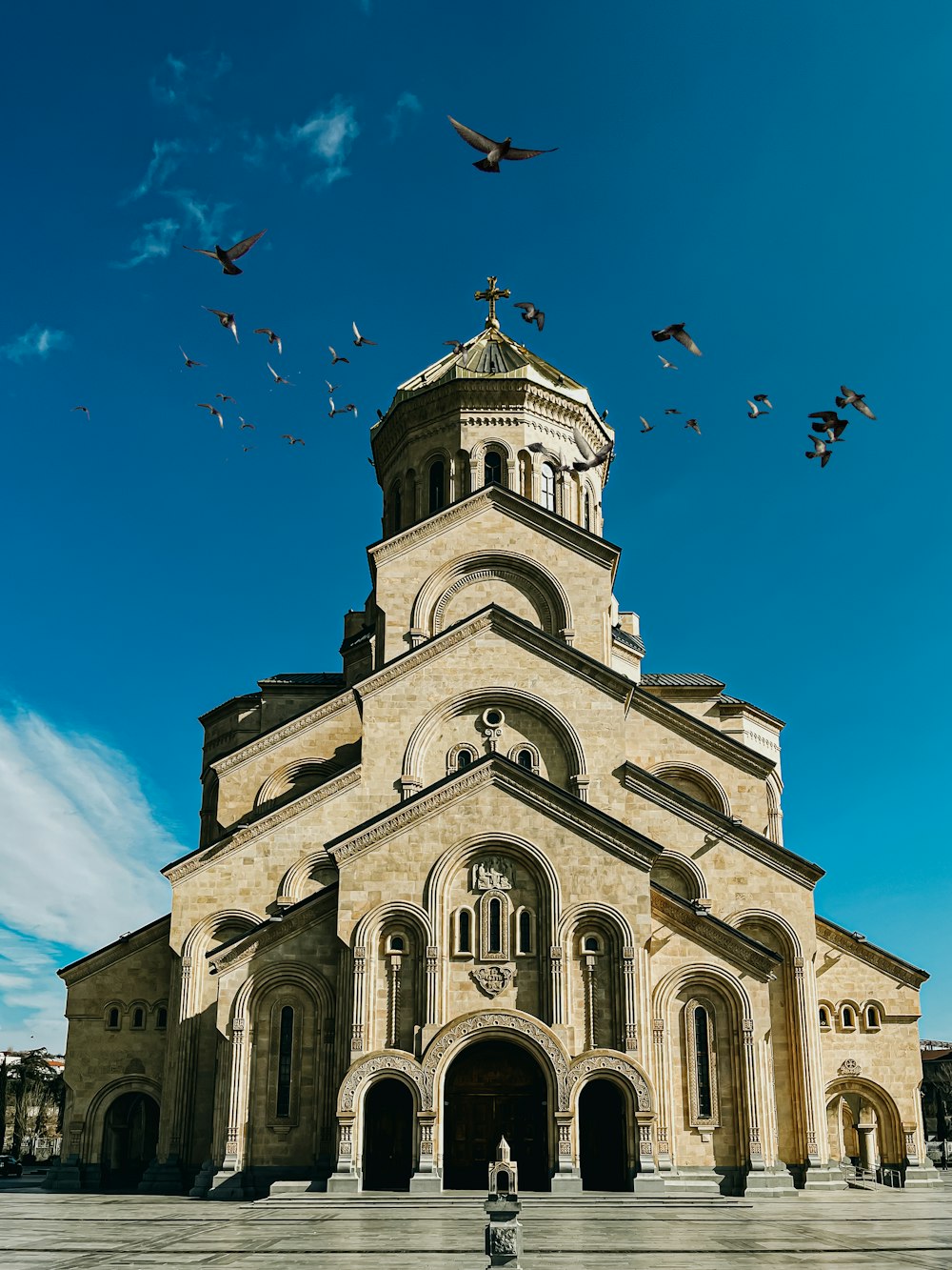 a large church with birds flying around it