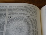 A close-up of an open book displaying text from the Old Testament. The pages show biblical passages, including numbered sections and some highlighted words.