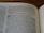 A close-up of an open book displaying text from the Old Testament. The pages show biblical passages, including numbered sections and some highlighted words.