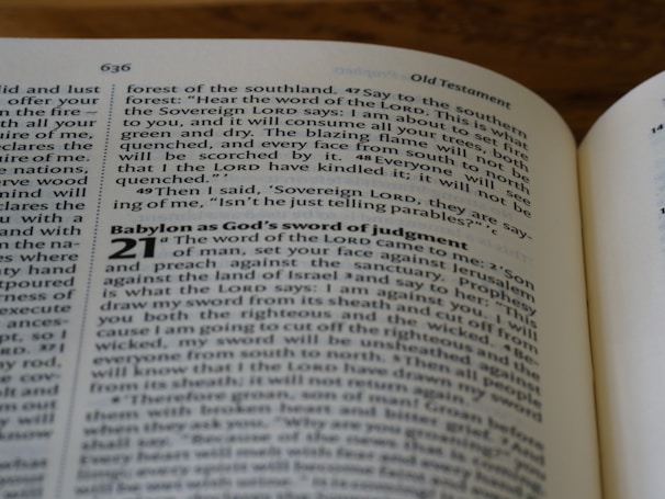 A close-up of an open book displaying text from the Old Testament. The pages show biblical passages, including numbered sections and some highlighted words.