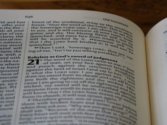 A close-up of an open book displaying text from the Old Testament. The pages show biblical passages, including numbered sections and some highlighted words.