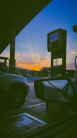 Fuel delivery truck unloading solar fuel at an industrial site during sunset
