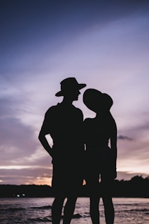 Sunset silhouette of a couple dressed in elegant Lumina Atelier outfits.