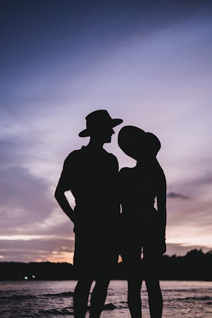 Sunset silhouette of a couple dressed in elegant Lumina Atelier outfits.
