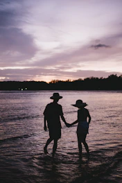two people standing in the water holding hands