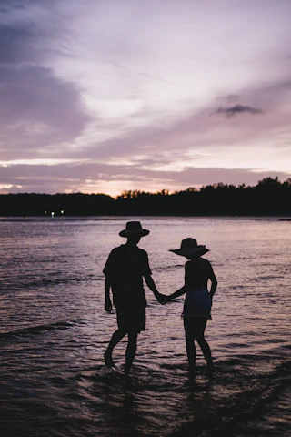 two people standing in the water holding hands