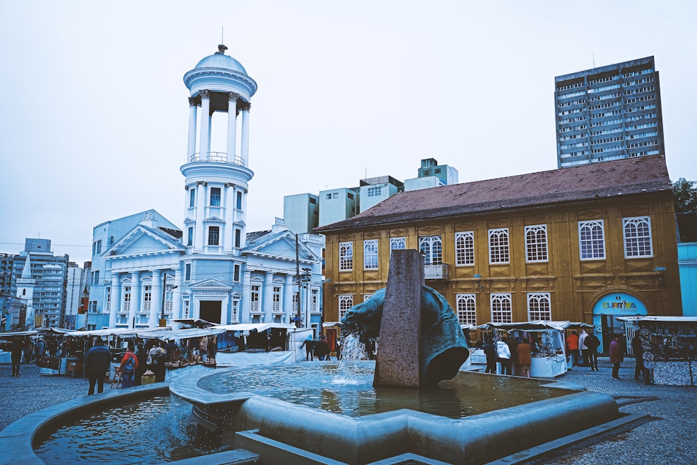 a fountain in front of a building with a clock tower in the background