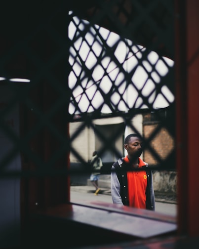 Young person wearing grey and black streetwear with neon orange accents in an urban setting.