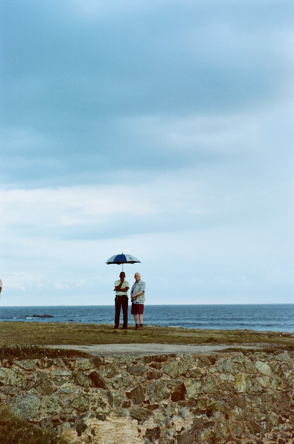 two people standing under an umbrella on a beach