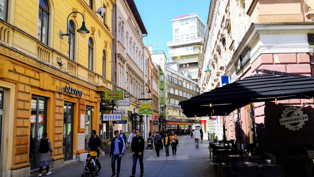 a group of people walking down a street next to tall buildings