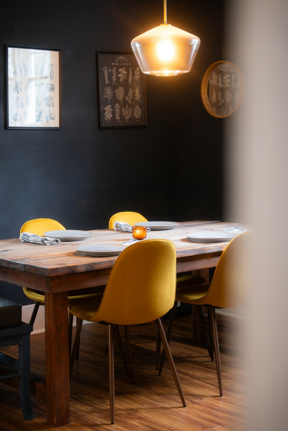 a dining room table with yellow chairs and a black wall