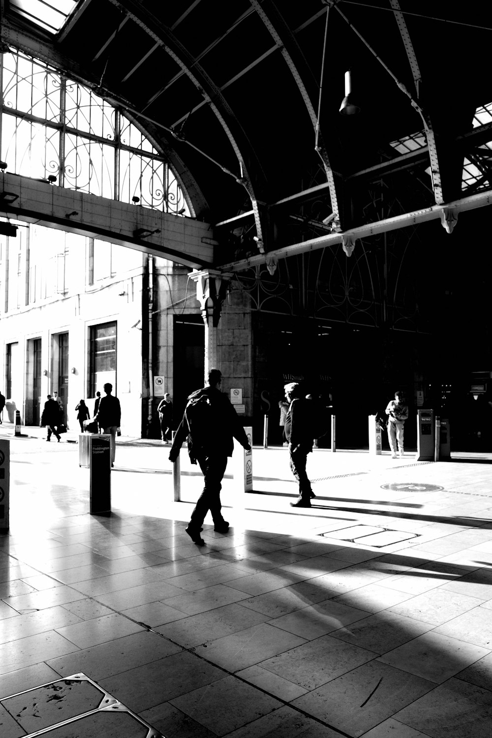 Ein Schwarz-Weiß-Foto von Menschen, die in einem Bahnhof spazieren gehen