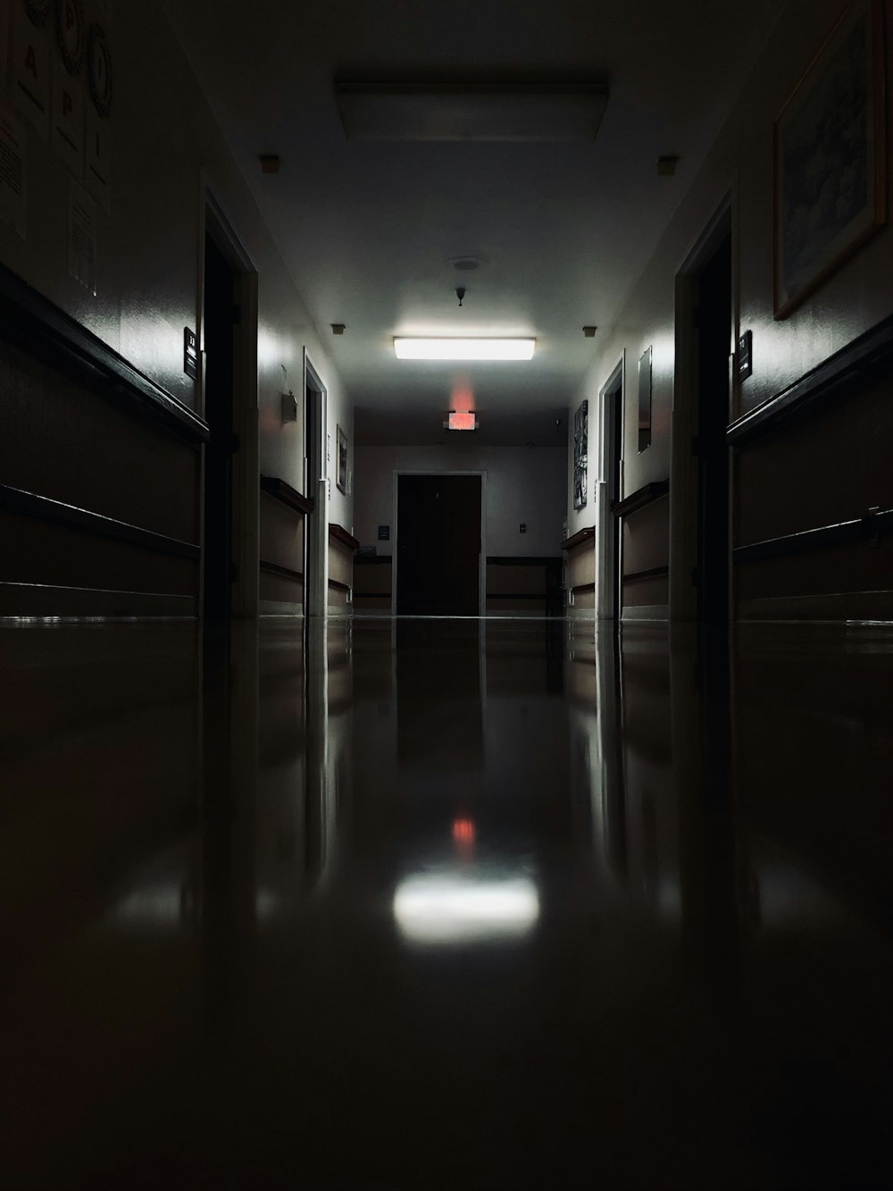 a dark hallway with a red light at the end of the hallway