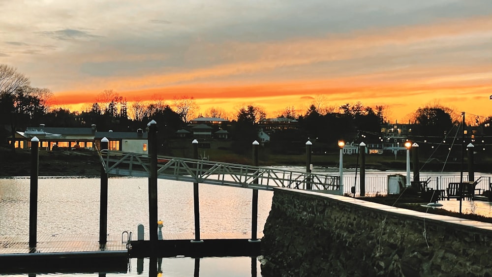 a dock with lights on and a sunset in the background