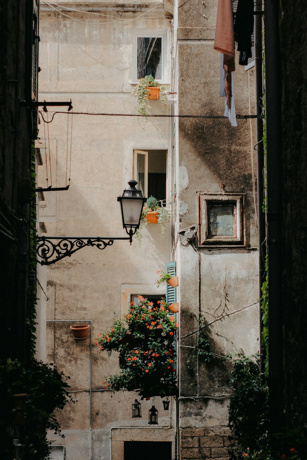 a narrow alley way with a lamp post and flowers