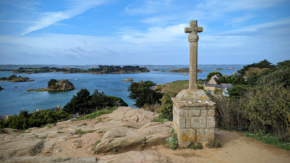 a cross on top of a rock near a body of water