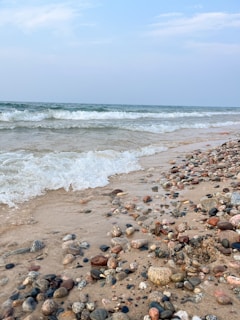 A quiet beach scene with turquoise waves gently lapping against smooth stones