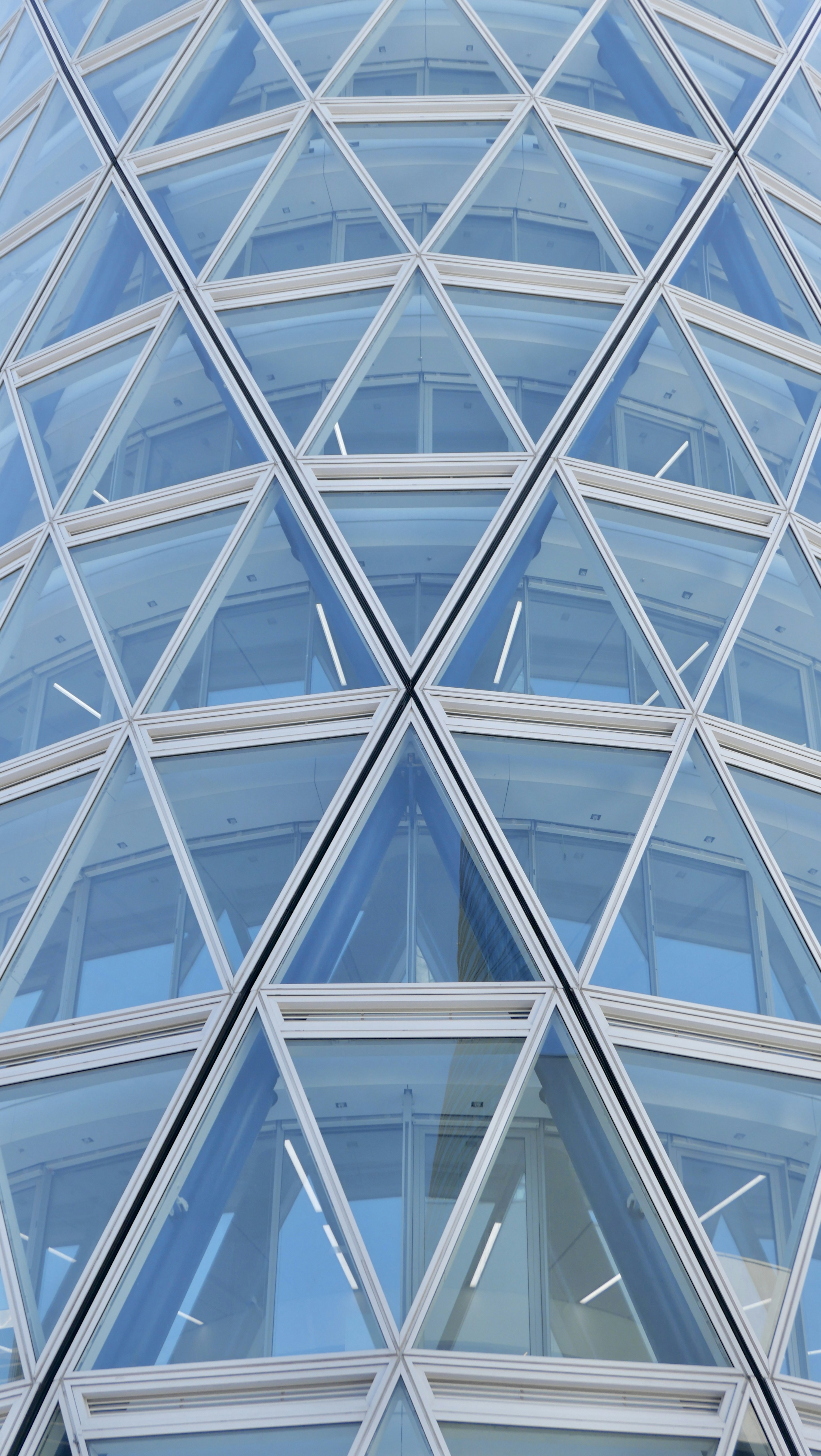 a very tall glass building with a clock on it's side