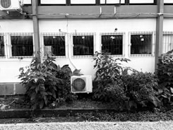 a black and white photo of an air conditioner in front of a building