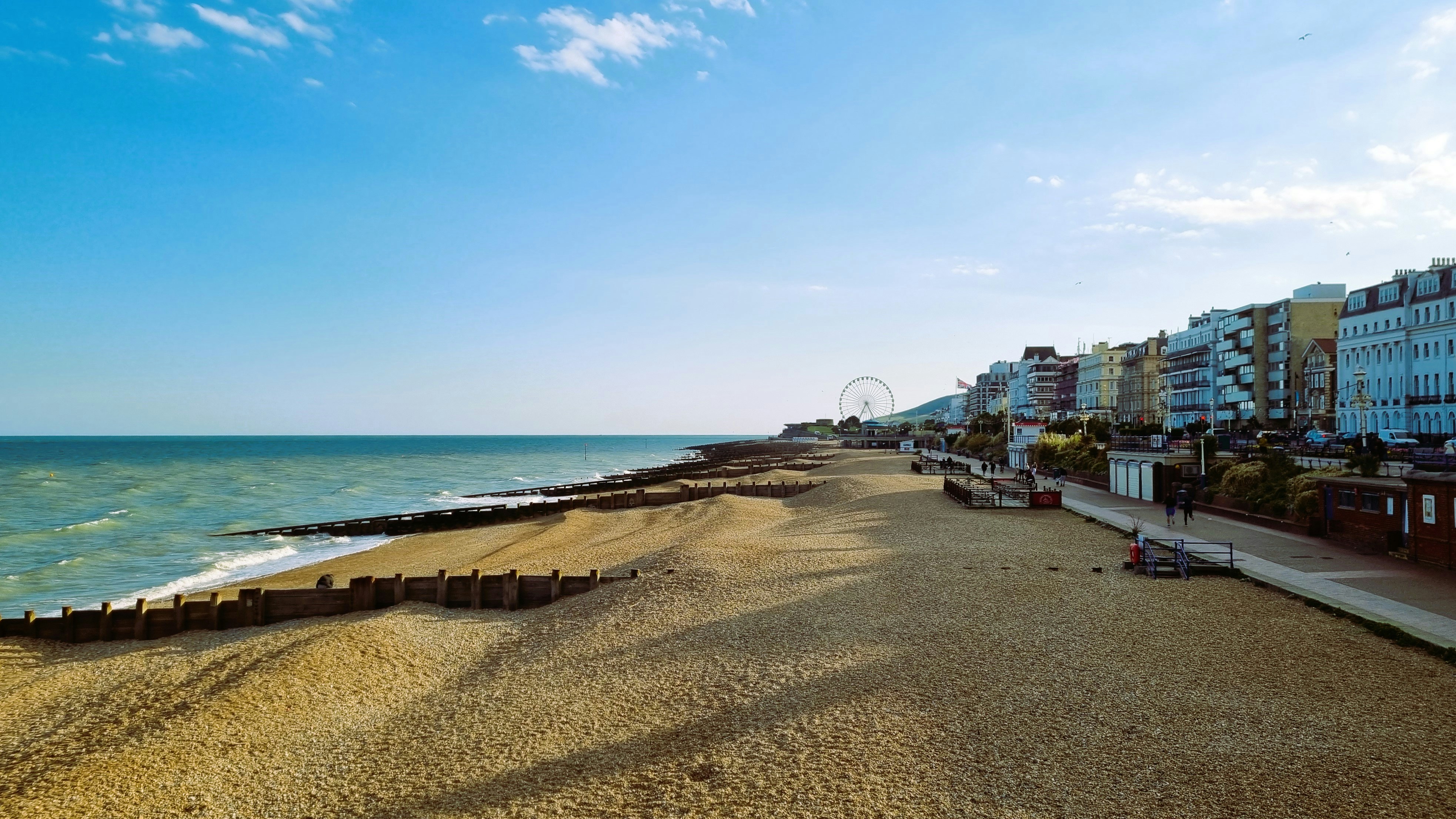 A sandy beach next to the ocean under a blue sky photo Free
