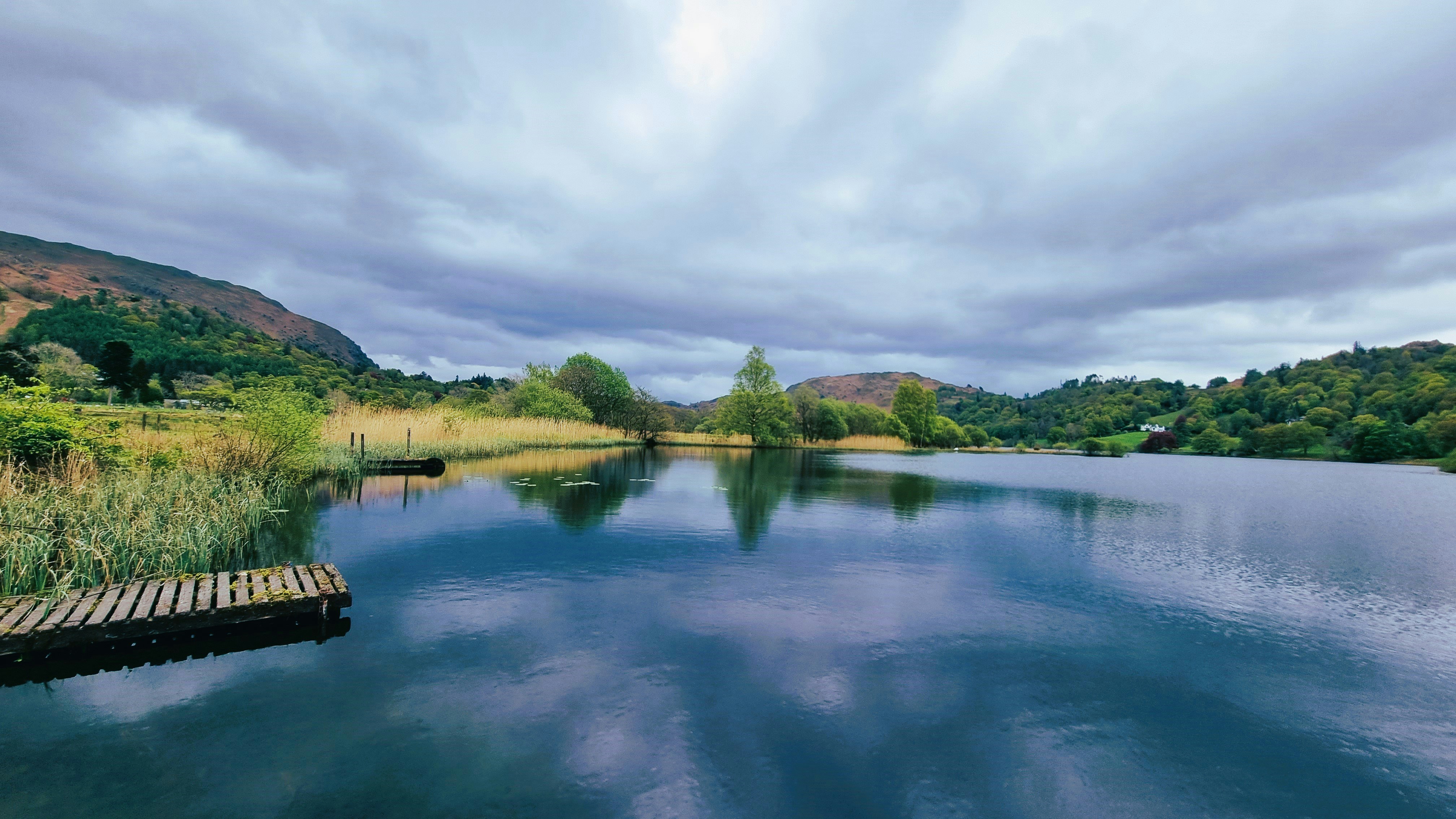 A body of water surrounded by a lush green hillside photo – Free Lake ...