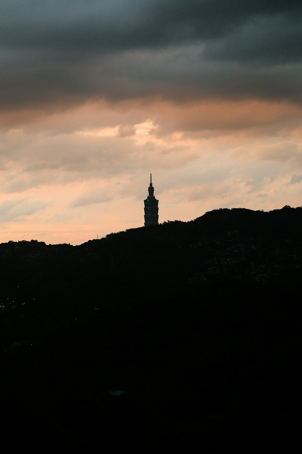 a clock tower on top of a hill under a cloudy sky