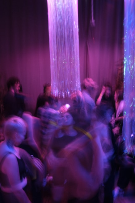 Guests enjoying a lively celebration under deep purple ambient lighting with modern decor.