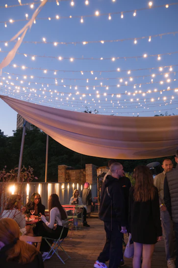 A cozy evening scene on the terrace with softly lit tables and guests enjoying cocktails under string lights.